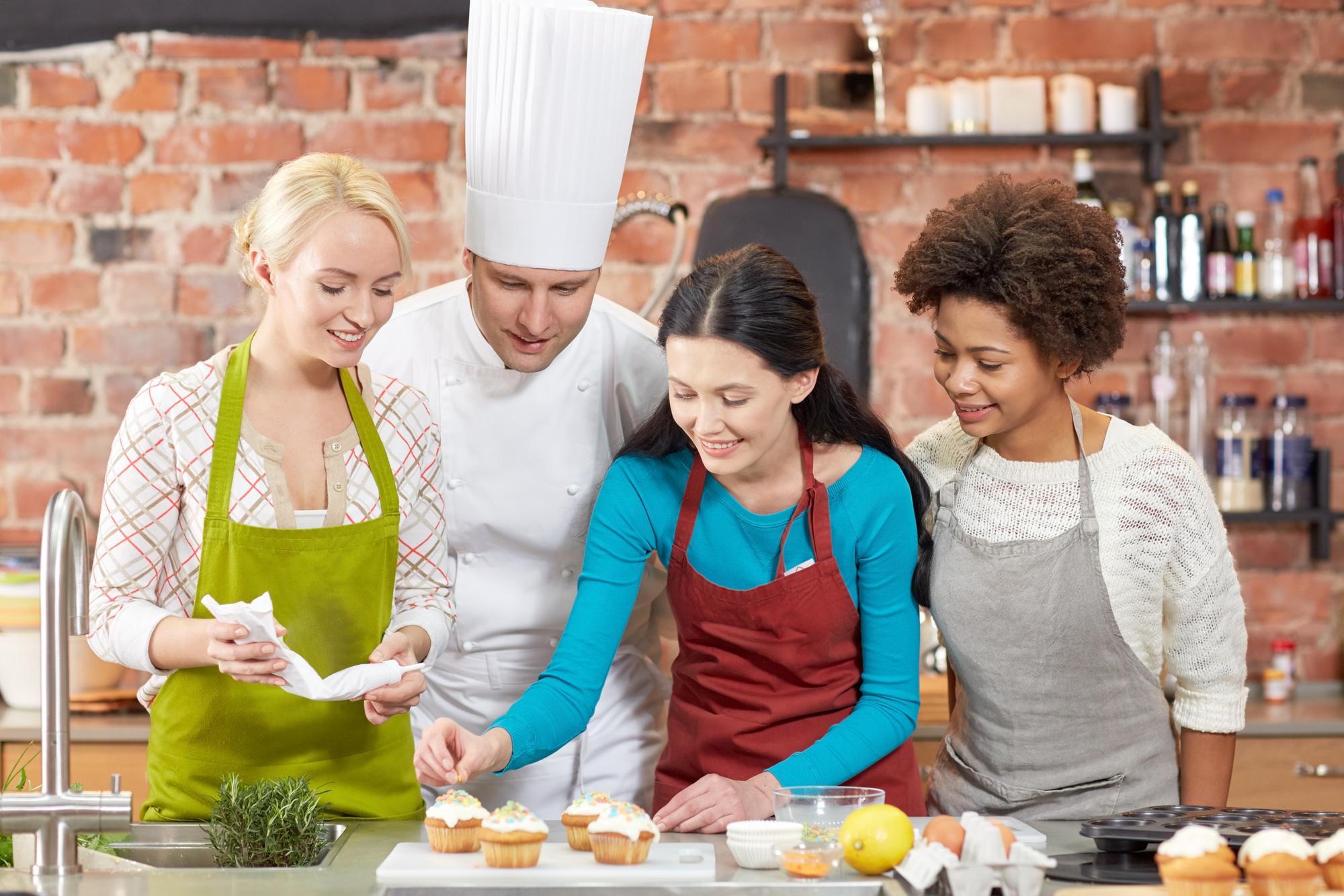 Students around a long wooden counter listening to chef